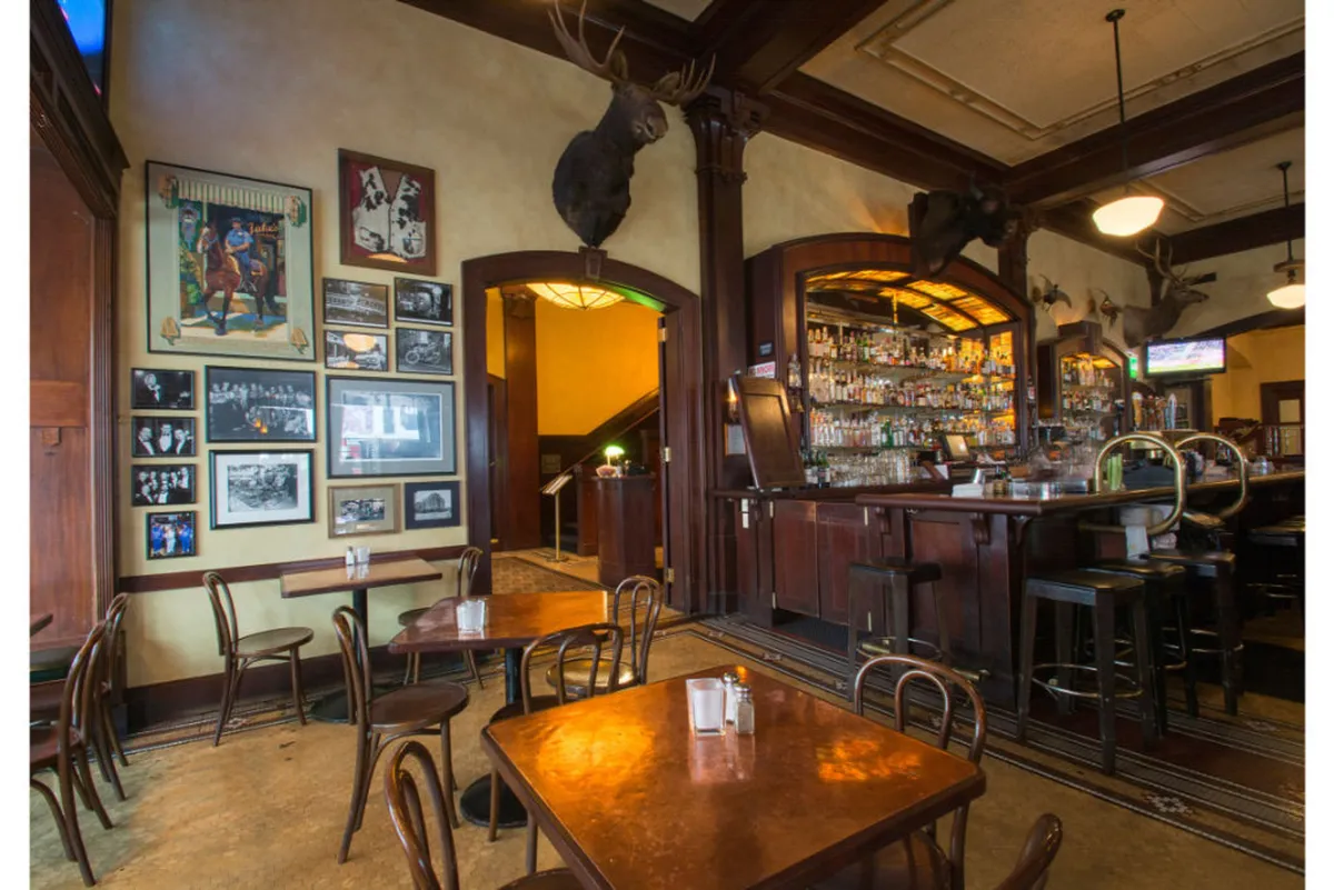 The image features a cozy lounge area with a stylish bar, walls adorned with historical and cultural photographs, and comfortable seating for socializing. The overall ambiance is nostalgic yet inviting, suggesting a space where creative minds can gather and connect.